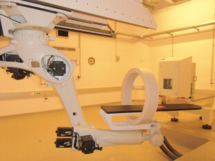 Medizinisches Gerät in einem Raum, mit beweglichem Arm und Tisch.