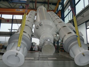 Großes technisches Bauteil in einer Industriehalle, möglicherweise ein Modell oder eine Komponente einer Rakete oder eines Raumfahrtgeräts.