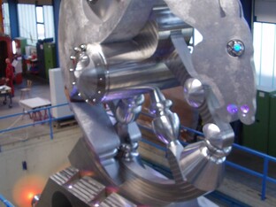 Eine Statue eines Pferdes, das aus stählernen Materialien hergestellt ist. Im Hintergrund ist eine Halle sichtbar.