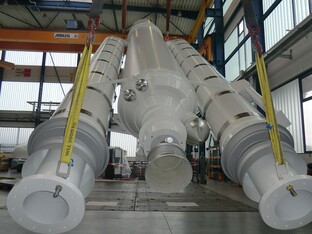Großes technisches Bauteil in einer Industriehalle, möglicherweise ein Modell oder eine Komponente einer Rakete oder eines Raumfahrtgeräts.