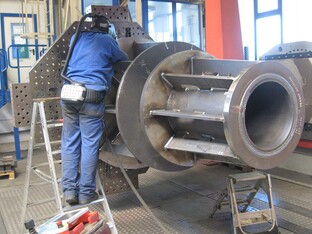 Industrielles Bauteil für den Royal Clock Tower mit vielen Komponenten. Eine Person, arbeitet an der Fertigstellung.