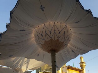 Schirmartige überdachungen, die in einer Reihe platziert sind. Im Hintergrund ist der blaue Himmel und eine Moschee sichtbar.