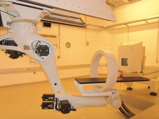 Medizinisches Gerät in einem Raum, mit beweglichem Arm und Tisch.