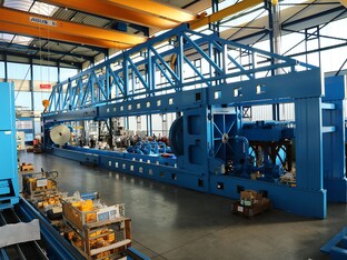 Die Montage einer Spiralrohrmaschine, auf einem blauen Gerüst in einer großen Halle.